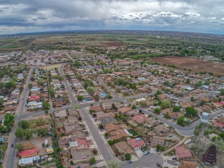 Aerial view of a suburban neighborhood with houses, streets, and green fields under a cloudy sky. water damage cleanup Bernalillo