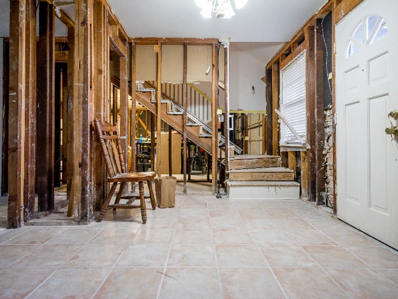Interior of a house under renovation with exposed wooden studs, a wooden chair, and a staircase. commercial water damage restoration