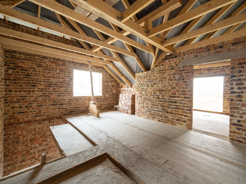 Unfinished attic space with exposed brick walls and wooden roof beams. disaster reconstruction services