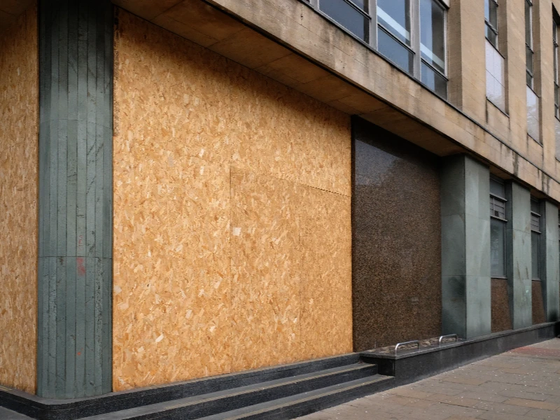 Building entrance boarded up with plywood panels and stone steps outside. emergency board up service emergency board up service